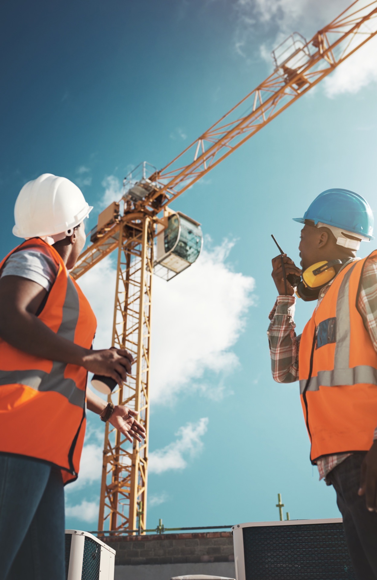 Construction engineering team on site with crane and safety equipment: car insured project in progress
