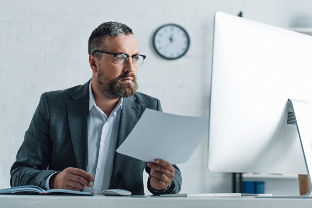 A professional insurance broker carefully reviewing policy documentation — berkley risk's specialist, policy-wording-first approach to commercial cover