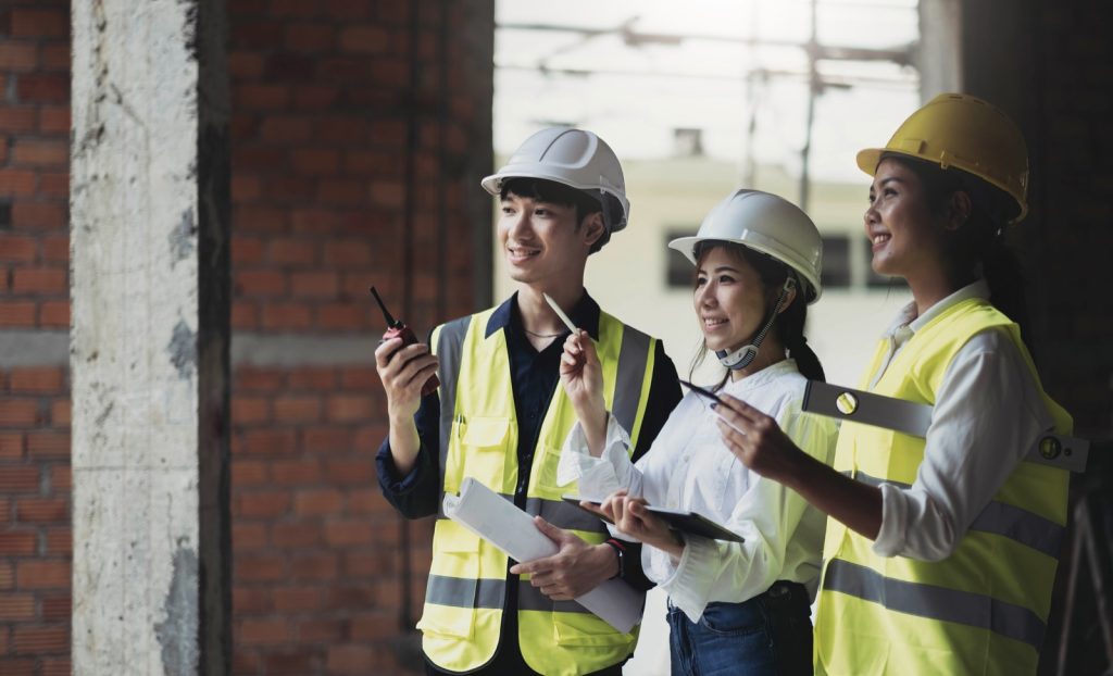 Architect and construction worker reviewing building plans on site, where design decisions create professional indemnity exposure for contractors