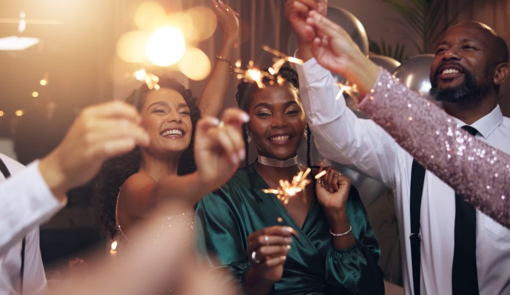 Colleagues in evening wear celebrating with sparklers at a year-end function